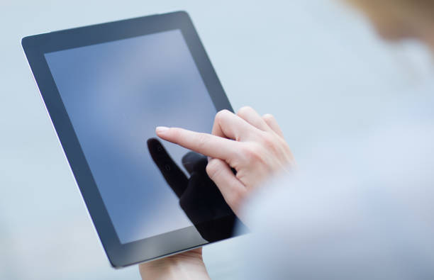 Close-up of a female person's hand and finger pressing on an electronic device.